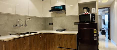 Una cocina moderna con microondas integrado, un lavamanos de acero inoxidable y armarios de madera.