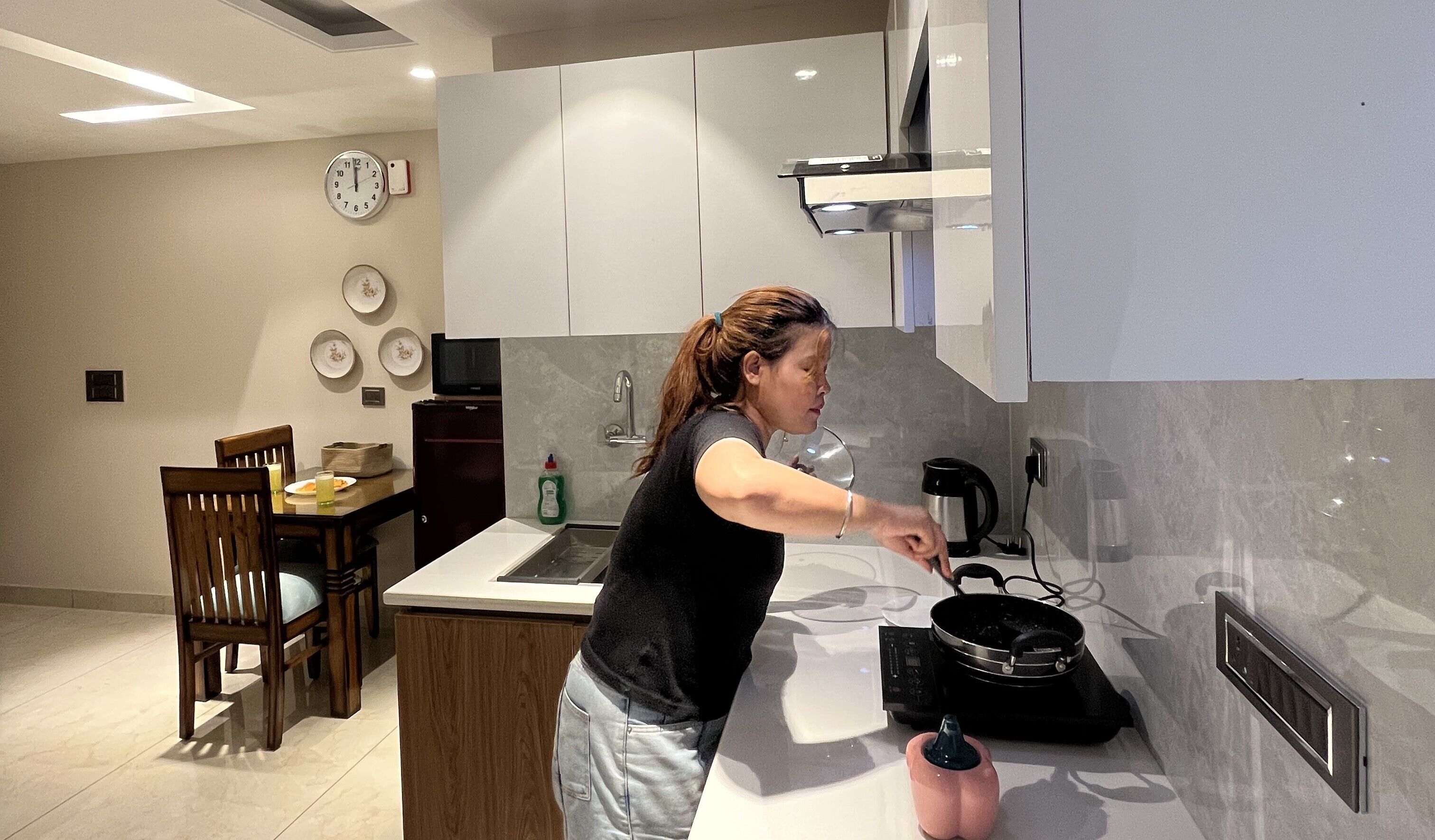 A modern kitchen with a central island, a dining area with a wooden table and chairs, and a microwave above the island.