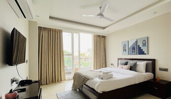 Una habitación de hotel con cama, televisor de pantalla plana, escritorio con teléfono y ventilador de techo.