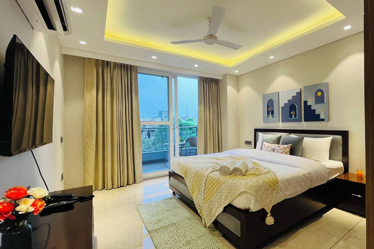 A modern hotel bedroom with a large bed, a ceiling fan, and a view of the outdoors through a sliding door.