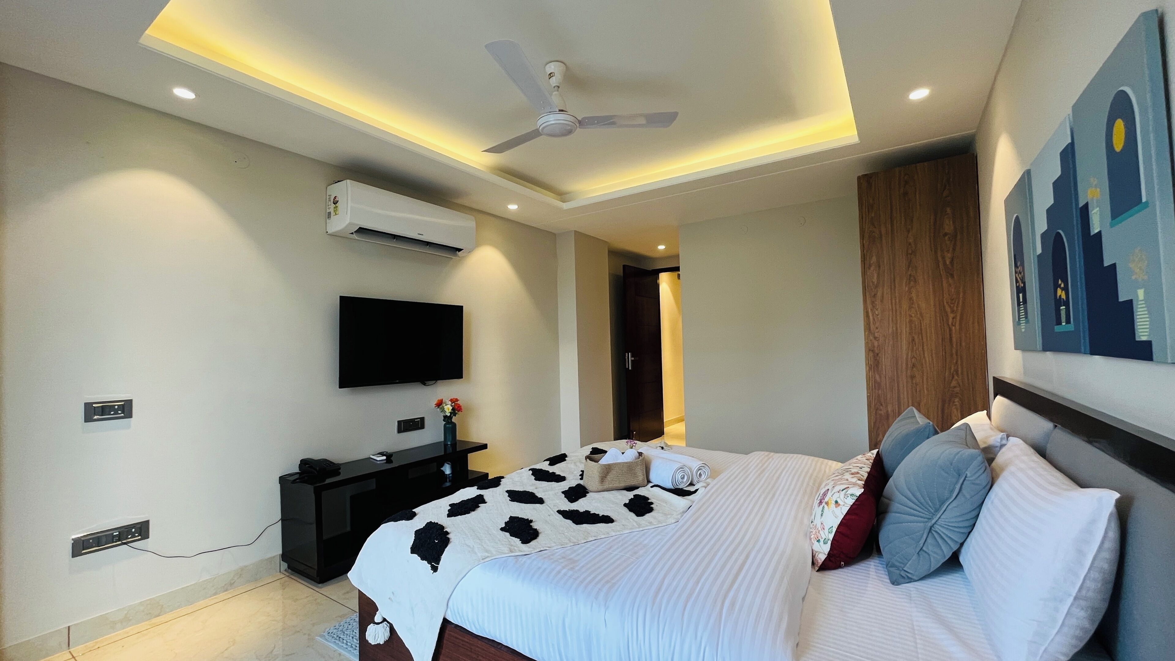 Un dormitorio moderno con cama, televisión de pantalla plana, ventilador de techo y aire acondicionado.