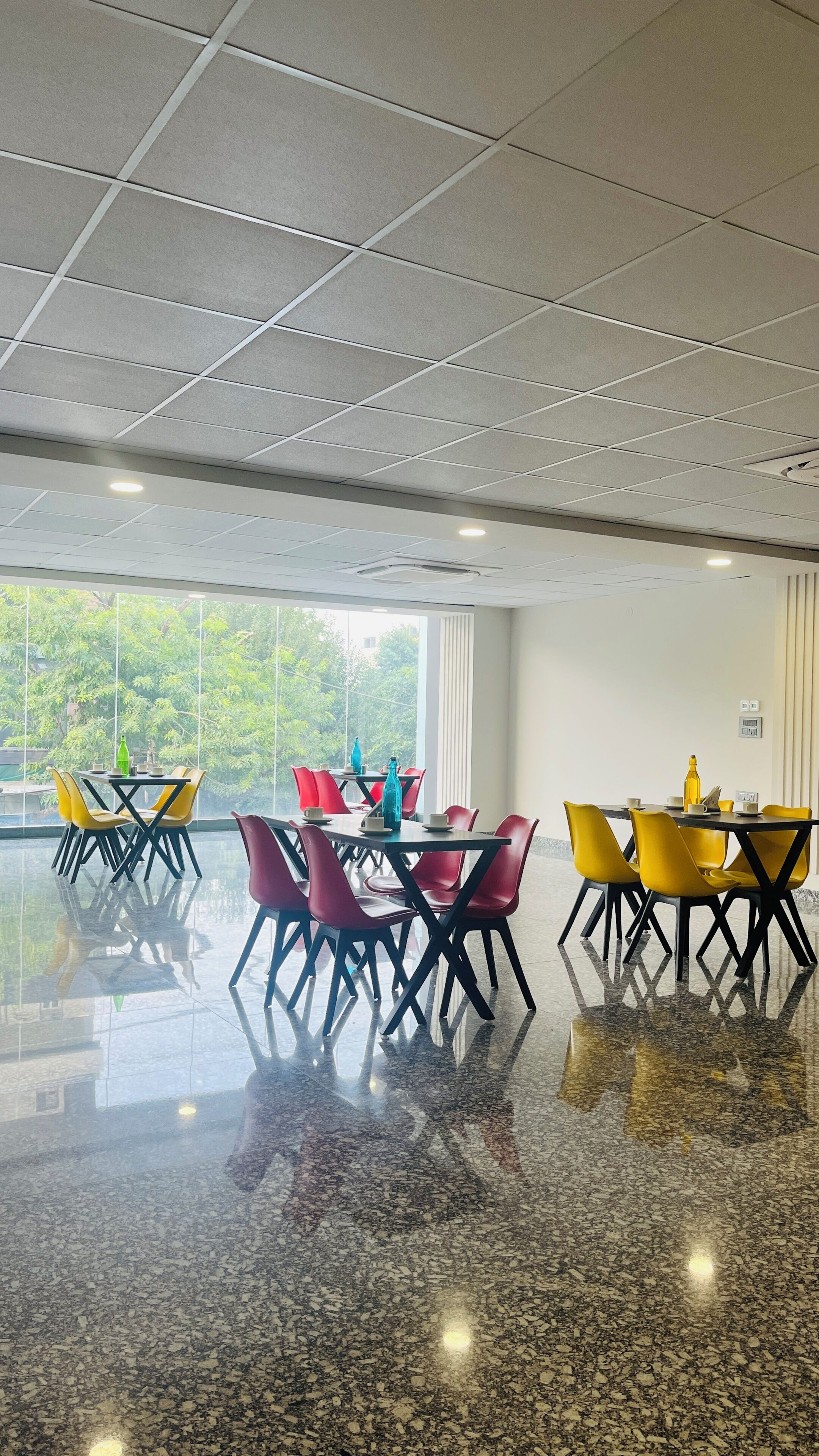 A spacious indoor area with a polished floor, large windows, and multiple tables with chairs.