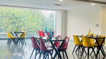 A spacious indoor area with a polished floor, large windows, and multiple tables with chairs.