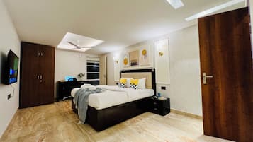 A modern bedroom with a bed, bedside tables, a desk, a TV, and a ceiling fan.