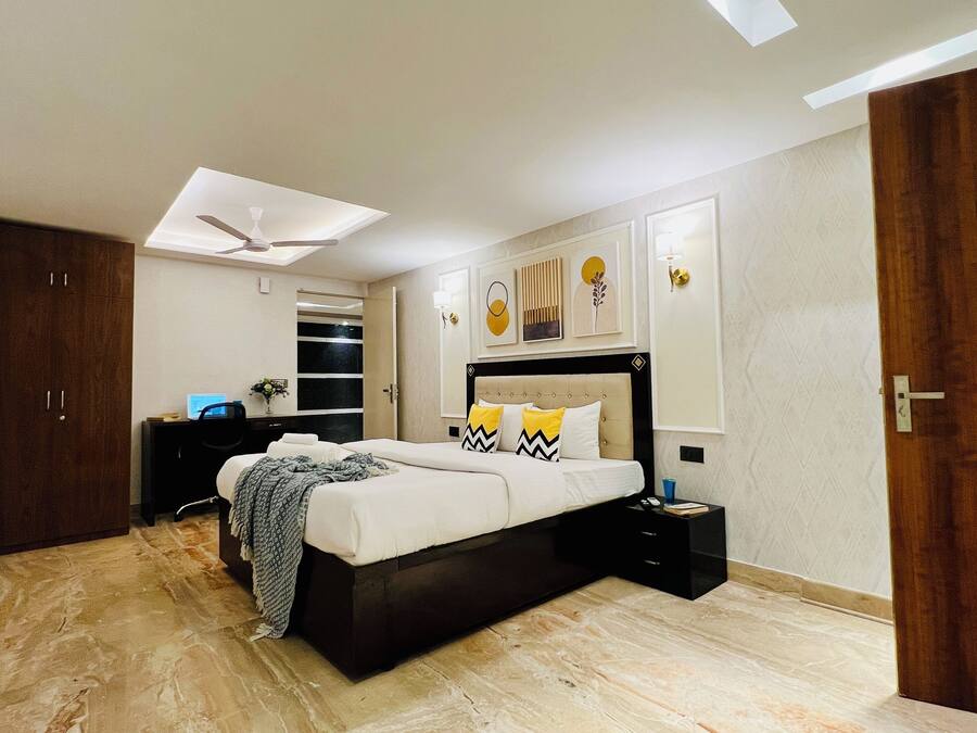A modern bedroom with a bed, bedside tables, a desk, a TV, and a ceiling fan.