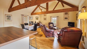 A spacious living room with a wooden ceiling, a dining area with a table and chairs, and a sofa. - Host & Stay | Widger Mews Apartment (Malton)