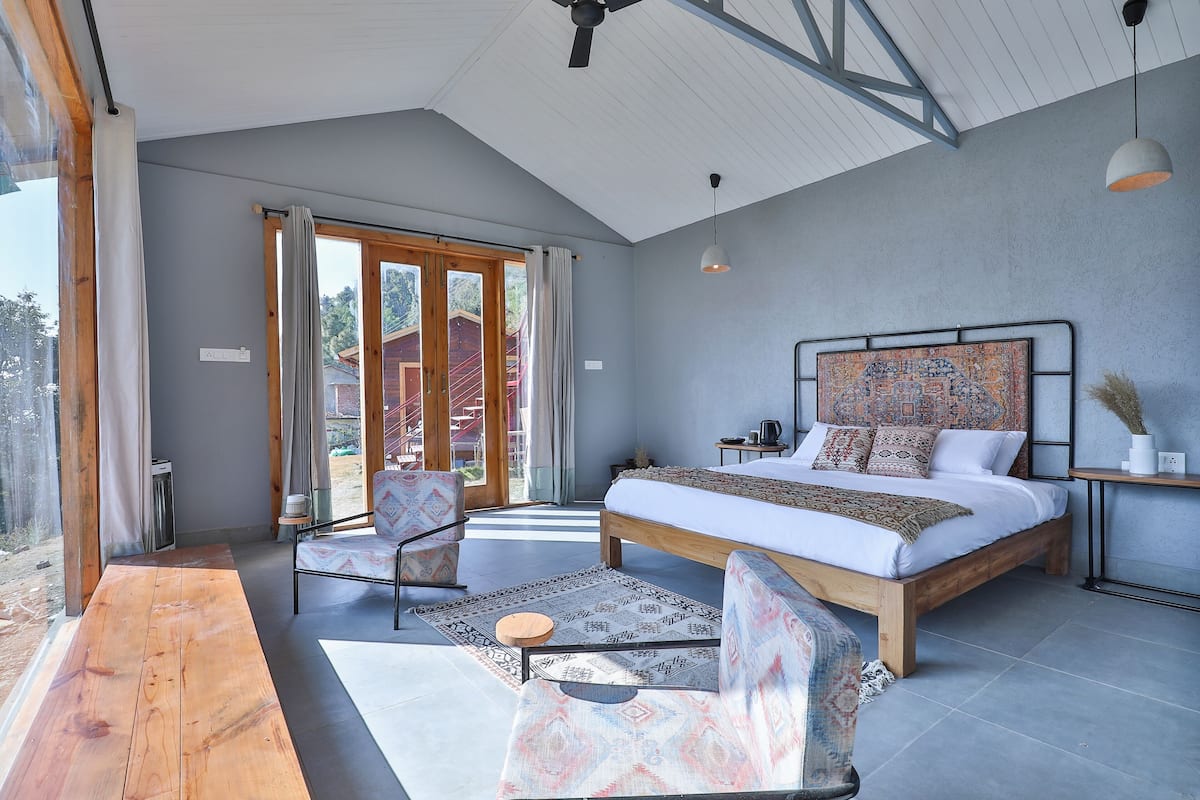 Une chambre spacieuse avec un grand lit, un plancher en bois et une vue à travers la porte vitrée.