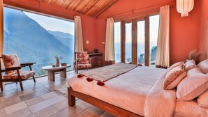 A bedroom with a large bed, wooden ceiling, and a view of mountains. - Seclude Pangot Perch (Nainital)