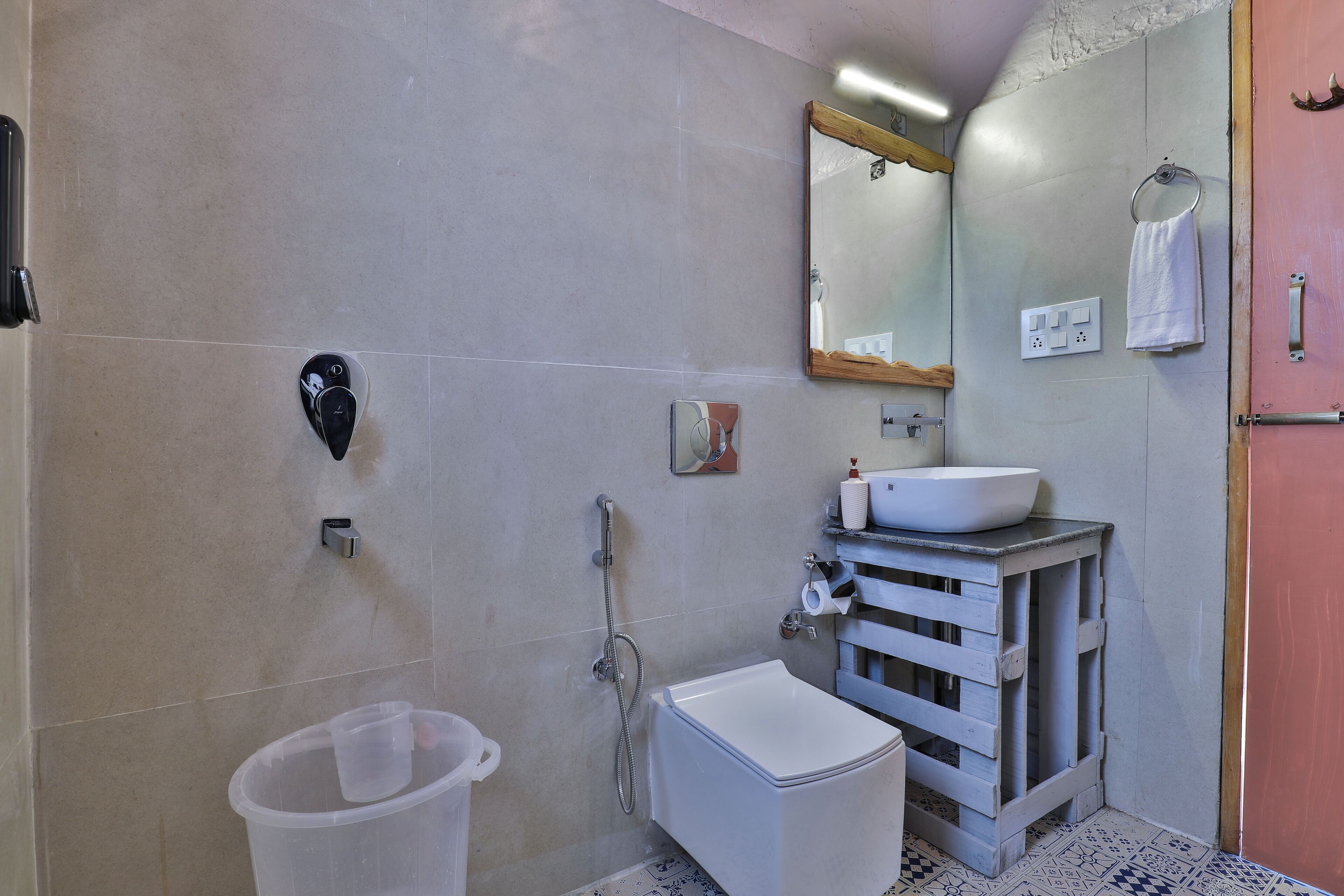 Un baño con inodoro, bidé, lavabo, espejo y un perchero para toallas.