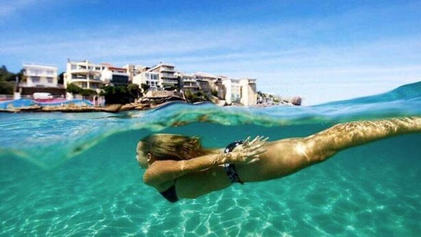 A person swimming underwater with buildings in the background. - Coogee Beach Escape | Pool & Balcony (Randwick)
