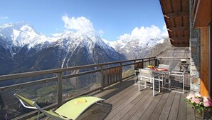 A wooden deck with a table and chairs, overlooking snow-capped mountains. - Chalet, 300m from ski slopes, fitness, hammam, balcony, fireplace or stove, parking, tv, 271m² (Les Deux Alpes)