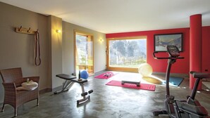 A gym with exercise equipment, a chair, and a window with a mountain view. - Chalet, 300m from ski slopes, fitness, hammam, balcony, fireplace or stove, parking, tv, 271m² (Les Deux Alpes)