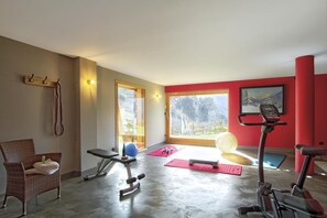 A gym with exercise equipment, a chair, and a window with a mountain view. - Chalet, fitness, hammam, balcony, fireplace or stove, parking, tv, 271m², Les 2 Alpes (Les Deux Alpes)