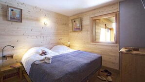 A wooden cabin bedroom with a bed, bedside lamp, and a window with a view. - Chalet, 300m from ski slopes, fitness, hammam, balcony, fireplace or stove, parking, tv, 271m² (Les Deux Alpes)