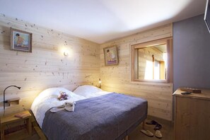 A wooden cabin bedroom with a bed, bedside lamp, and a window with a view. - Chalet, fitness, hammam, balcony, fireplace or stove, parking, tv, 271m², Les 2 Alpes (Les Deux Alpes)