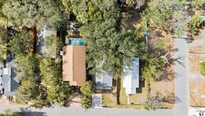 Luchtbeeld van een woongebied met huizen, bomen en een zwembad.