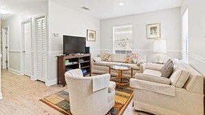 Een woonkamer met een bank, fauteuils, een salontafel en een tv op een dressoir.