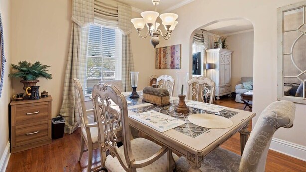 Comedor con candelabro, una mesa preparada para cuatro comensales y vista a otro ambiente.