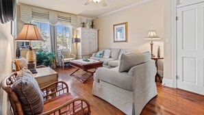 Una sala de estar con sofá, sillón, mesa de centro y ventilador de techo.