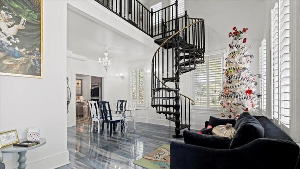 Ein großzügiger Wohnbereich mit einer schwarzen Wendeltreppe, einem weißen Weihnachtsbaum und einem Essbereich mit Stühlen und Tisch.