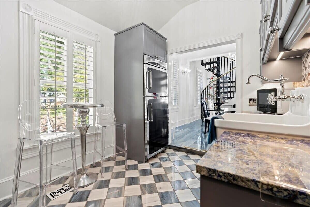 A modern kitchen with a checkered floor, a stainless steel refrigerator, and a marble countertop.