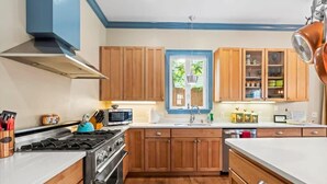 A kitchen with wooden cabinets, a stove, a microwave, and a window.
