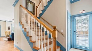 A staircase with white balusters and wooden handrails, leading to a blue door with an 'EXIT' sign above it.