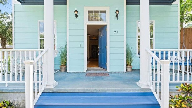 A light blue house with white trim, a blue front door, and the number 71 on the door.