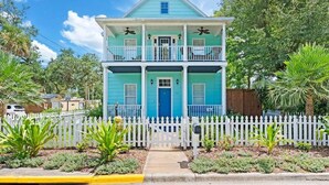 A two-story house with a blue exterior, white trim, and a white picket fence.