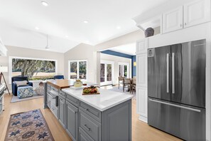A modern kitchen with a large island, stainless steel refrigerator, and a view to the outdoor patio. - New Reno! Seabrook amenities and beach access (Seabrook Island)