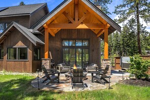 Eine Holz-Blockhütte mit einer überdachten Terrasse, Sitzgelegenheiten im Freien und einem Feuerkorb.
