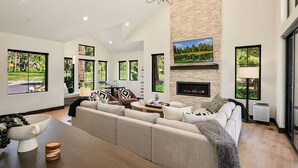 Un salón espacioso con chimenea, ventanas amplias y vistas al exterior.