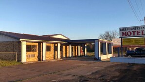 A motel with a covered parking area and a signboard. - Lake Country Inn  (Trinity)