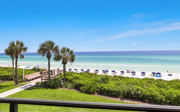 A beach with palm trees, a wooden deck, and umbrellas. - Views of the Gulf, Private Beach Access, & Bikes (Santa Rosa Beach)