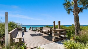 A wooden deck with benches, a palm tree, and a view of the ocean. - Views of the Gulf, Private Beach Access, & Bikes (Santa Rosa Beach)