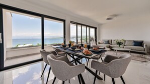 A modern dining area with a view of the sea, a sofa, and a coffee table.