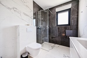 Un baño moderno con ducha de vidrio, inodoro y bañera.