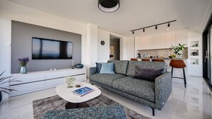 Ein modernes Wohnzimmer mit einem grauen Sofa, einem Couchtisch und einem flachbildfernseher an der Wand.
