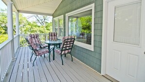 Une véranda avec une table et des chaises, de grandes fenêtres et une porte blanche.