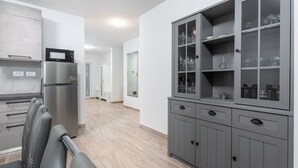 A modern kitchen with grey cabinetry, a built-in microwave, and a seating area with a chair and a table. - Lovely Villa Buroli with swimming pool, jacuzzi and sauna (Buroli)