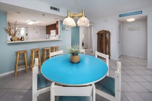 Un comedor con una mesa azul, sillas blancas y una lámpara colgante.