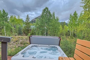A hot tub with a wooden bench, surrounded by trees and a mountain in the background. - Hawn Drive 62 4 Bedroom Townhouse by RedAwning (Frisco)