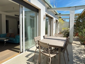 An outdoor patio with a table and chairs, a sliding glass door leading to a room, and a garden area with plants. - Milano City Design Apartment: modern and stylish house with terrace, city center (Milano)