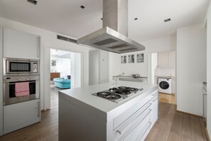 A modern kitchen with a central island, built-in oven, microwave, and a washing machine in the adjacent room. - Milano City Design Apartment: modern and stylish house with terrace, city center (Milano)