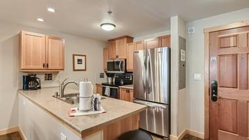 A kitchen with wooden cabinets, stainless steel appliances, and a central island with a sink and a kettle.