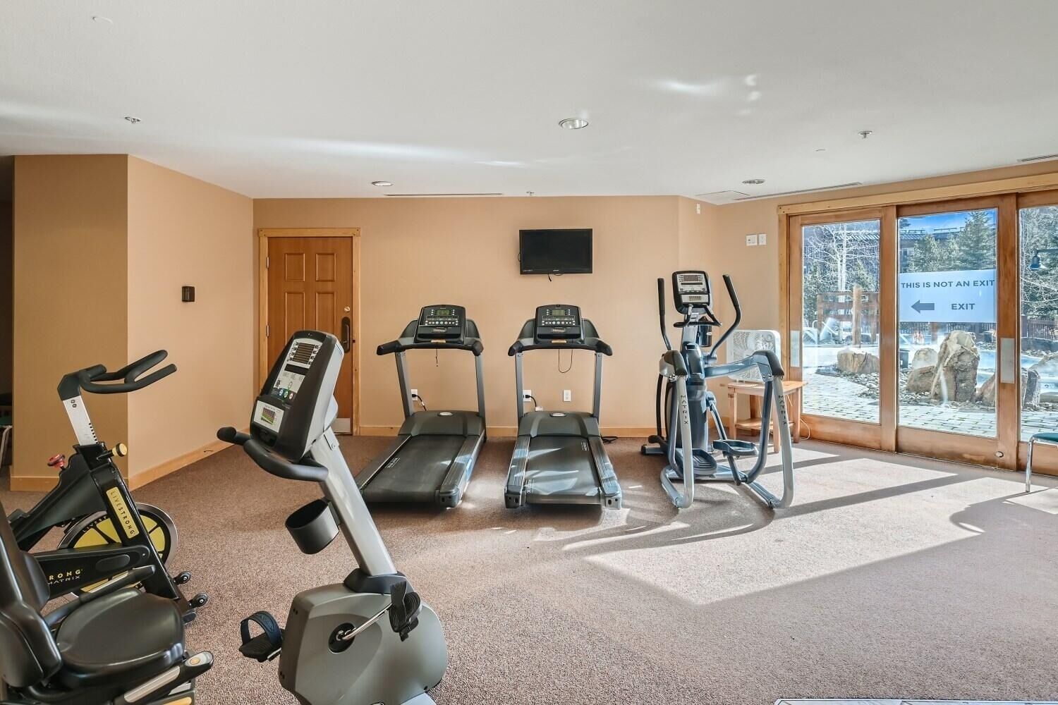 Un gimnasio con cintas de correr, elípticas y bicicletas estáticas.