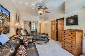 A bedroom with a bed, a wooden dresser, a television, and a ceiling fan. - Passage Point 623 2 Bedroom Condo by RedAwning (Copper Mountain)