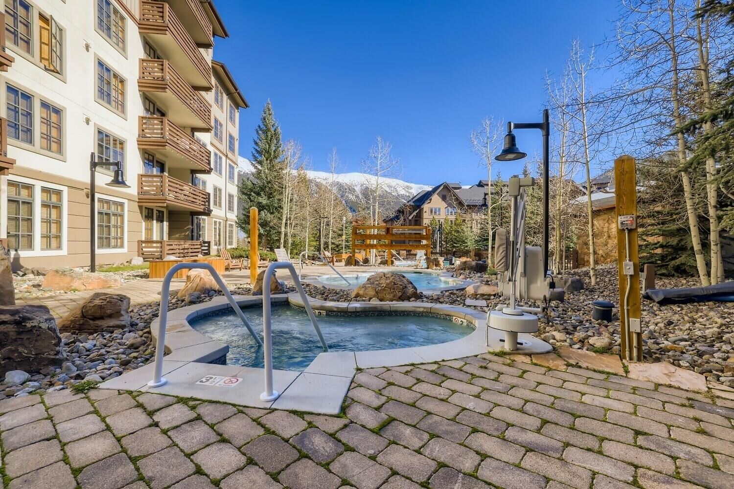 A hotel with a pool area, outdoor seating, and a mountain backdrop.