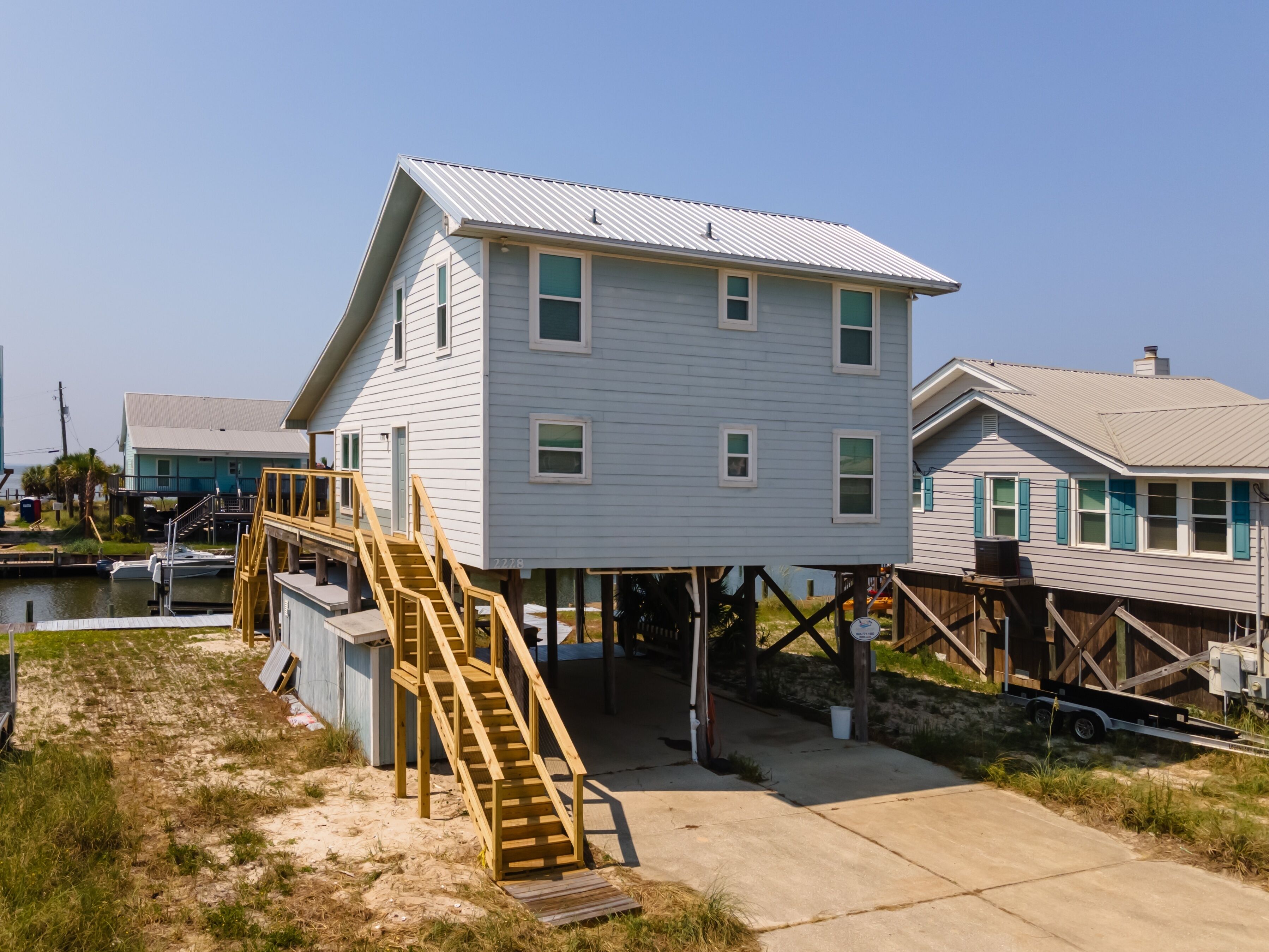 A two-story house with a wooden deck and stairs leading to a covered area.