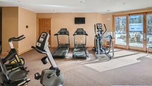 Un gimnasio con cintas de correr, elípticas y bicicletas estáticas.